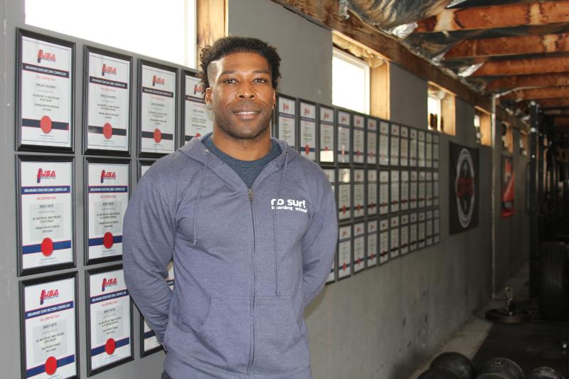Will Harris, owner and operator of Rehoboth Beach Barbell Club, stands by a wall of state records earned by his members. MELISSA STEELE PHOTOS