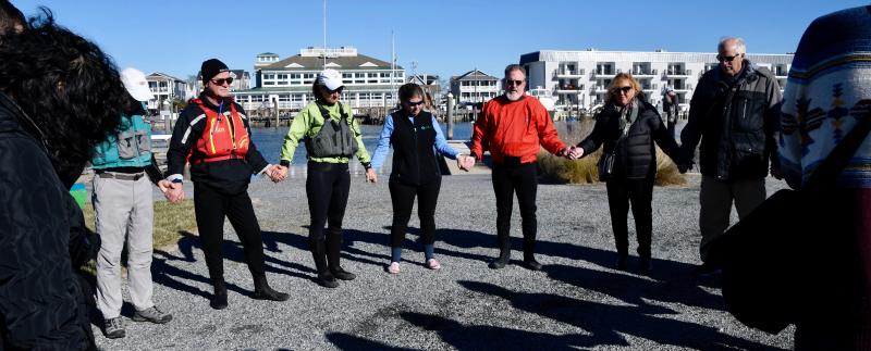 Club members join in a friendship circle to share thoughts and say a prayer before they begin to paddle.