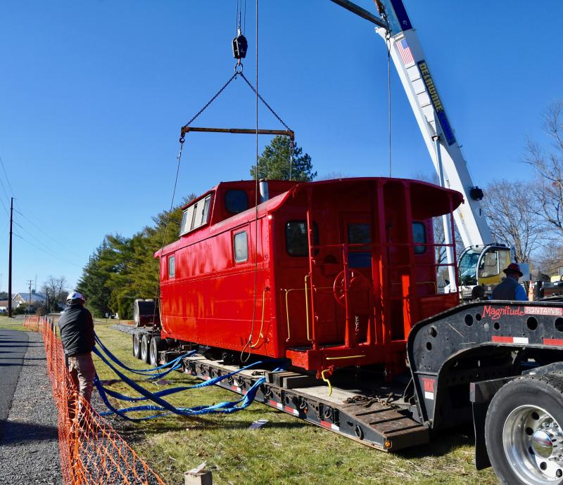 The caboose is hoisted off a large trailer to be placed on the railroad tracks after a move from Georgetown.