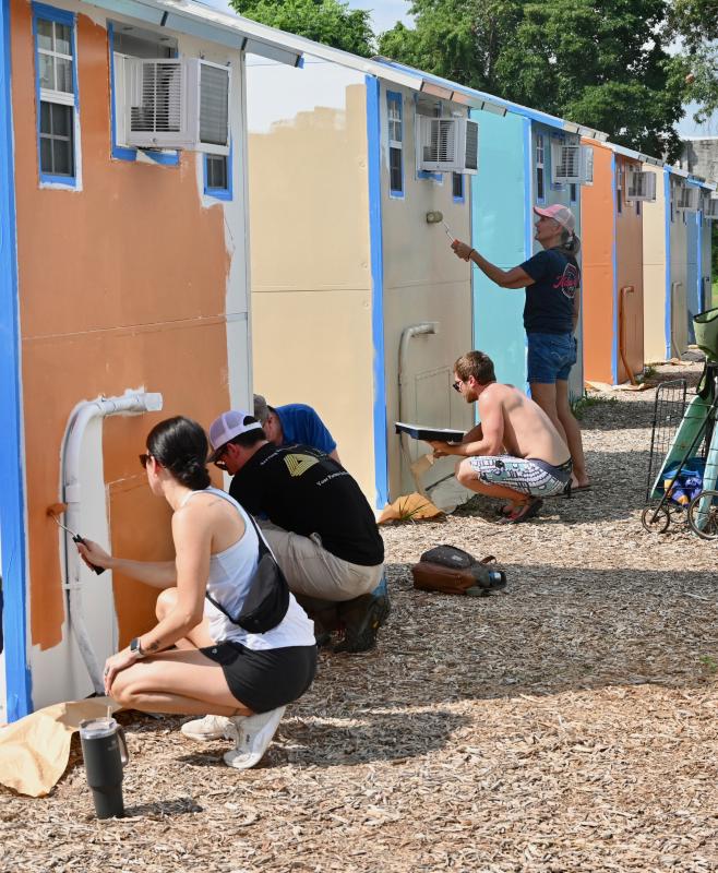 A row of Pallet Village cottages are getting painted July 7 during the second day of the Paint the Town project.