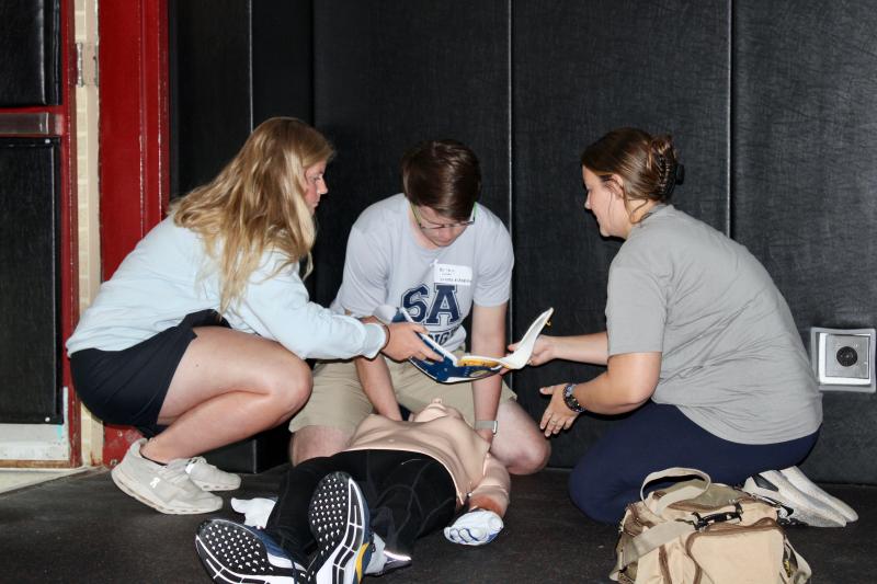 Cape Henlopen High School athletic trainers Ashley Schuster, left, and Hollyann Wettstein, right, work with Sussex Academy athletic trainer Brian Hubeler during an Aug. 4 training scenario at Polytech High School in Woodside. AARON MUSHRUSH PHOTOS