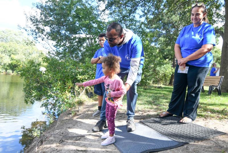 John Collins helps his daughter Topanga throw a flower to remember the loss of her unborn sister as her brother Malachi and her mother Ashley look on.