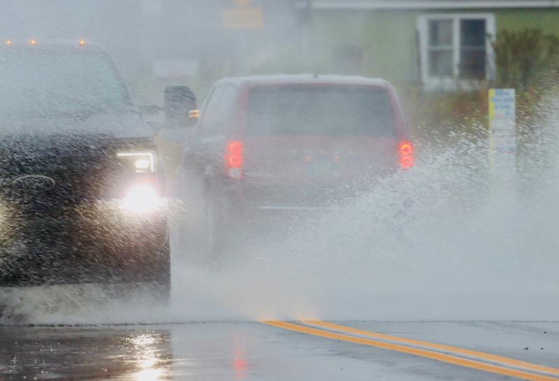 Vehicles splash through minor flooding on Savannah Road, near Otis Smith Park in Lewes. BILL SHULL PHOTO