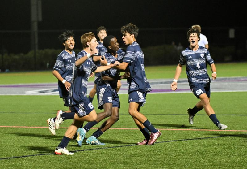 The Sussex Academy team rushes to congratulate Jesse Jean-Louis on his goal.