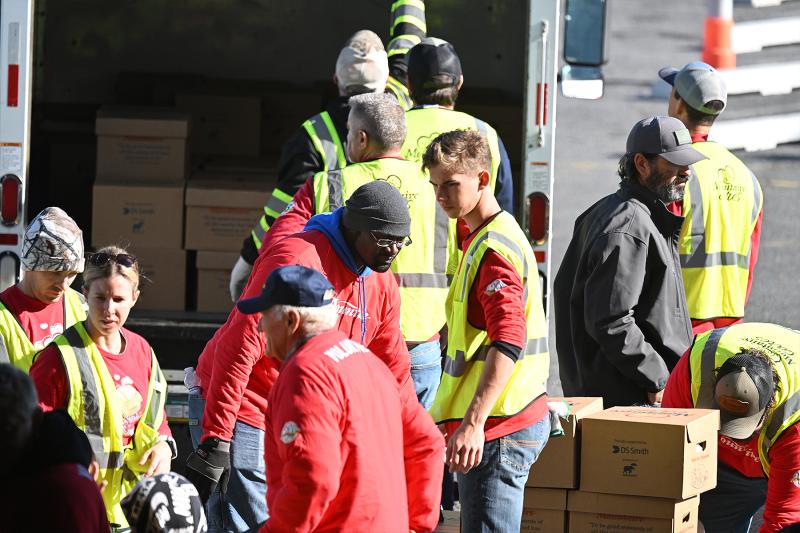 Workers pack individual meal boxes onto cars, trucks and vans for distribution to families in need.