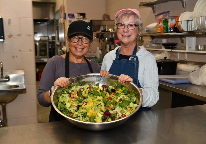 Sandi Mosher, left, and Janet Brownback prepare the salad for the free soup kitchen meal.