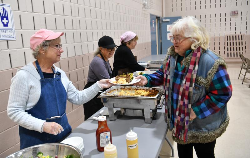 Elisha Baker, right, gets her meatloaf meal from volunteer Janet Brownback