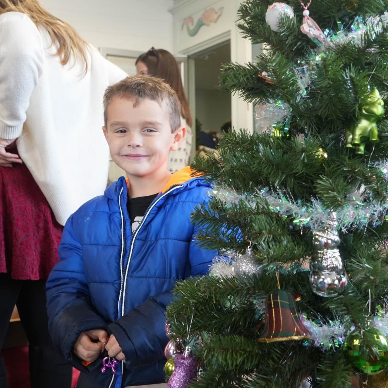 Pierce Kenton, 5, smiles with an ornament beside the Christmas tree his family is decorating.
