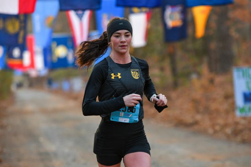 Women’s half-marathon winner Lydia Olivere cruises through Flag Alley on the way to a time of 1:17:54.
