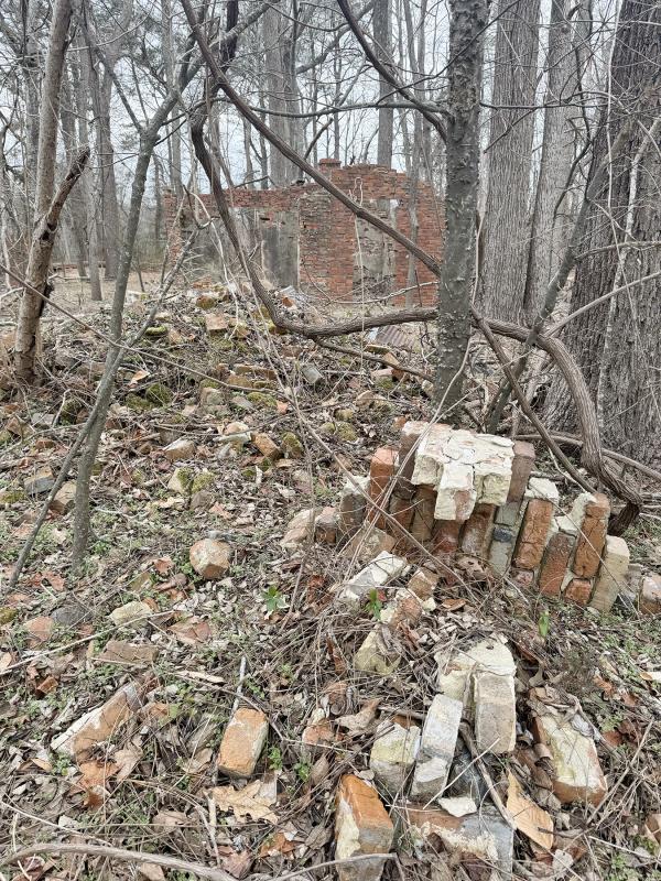 A pile of bricks sits along Round Pole Bridge Road with the shell of a former brickyard building behind. NICK ROTH PHOTO