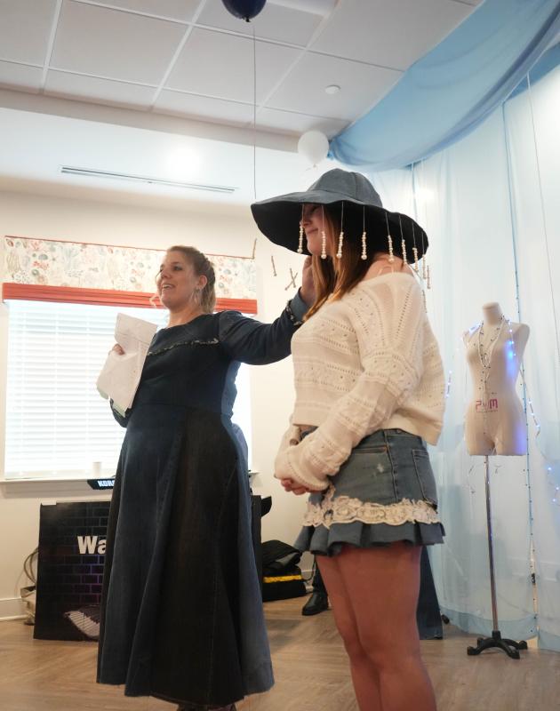 Cape fashion teacher Alayna Aiken, left, points to the denim hat with pearls, designed by classmate Taylor Ruark, that junior Baylei Lehman is modeling. Lehman is also modeling a denim skirt with box pleats and antique lace.