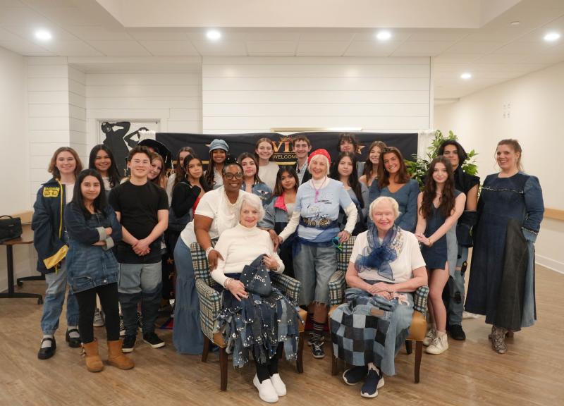 Cape fashion students and their teacher, Alayna Aiken (far right), smile with the Lodge’s Director of Programming Reshell Truitt, standing on the left in the front row by the chair, and the three Lodge residents who modeled the students’ designs: June Walters (front left, sitting), Ellie Hoffman (front middle, standing) and Helen Janson (front right, sitting). Shown in back are (l-r) students Madyson Morgan, Val Imperial, Baylei Lehman, Taylor Ruark, Brianna Holston, Illiana Colon, Sophia Leposki, Kellen Leposki, Stella Holmes, Ryleigh Moyer, Benjj Chau and teacher Alayna Aiken. In middle are (l-r) are Alexa Ayella, James Sparks, Sarai Vivar-Lucero, Melanie Buruca-Calderon, Alison Cruz-Delgado, Alexandria Espinoza, Milena Buehler and Madeline Cordrey.