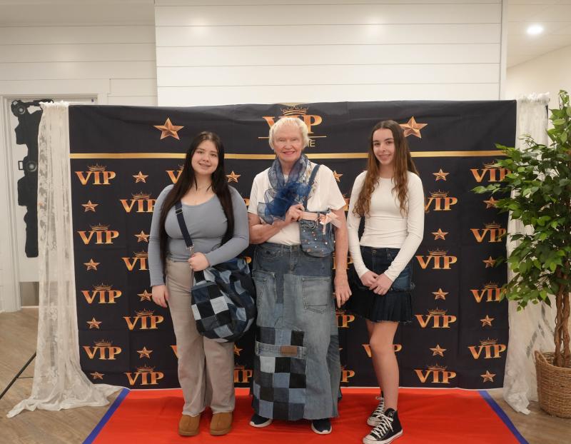 Students Alexandria Espinoza, left, and Brianna Holston stand with Lodge resident Helen Janson, who’s modeling garments they designed for her. Espinoza designed the quilted skirt, and Holston designed the purse.