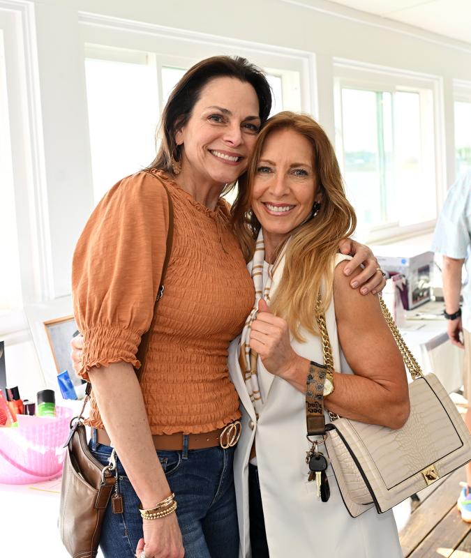 Friends Dina Donofrio, left, and Cyndi Franco pose for a picture at the silent auction display.