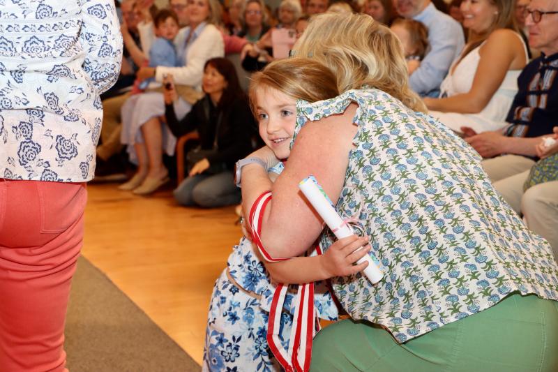 Hope Coulter from the Penguin class gets a hug from teacher Amy Casas after she got her diploma.