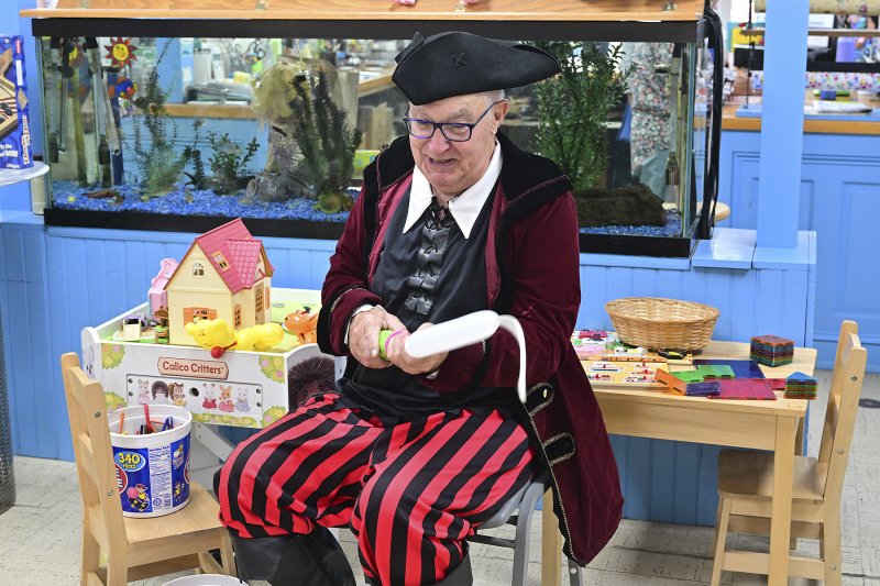 Tom Greenwood, aka Chuckles the Pirate, twists balloon animals for children.