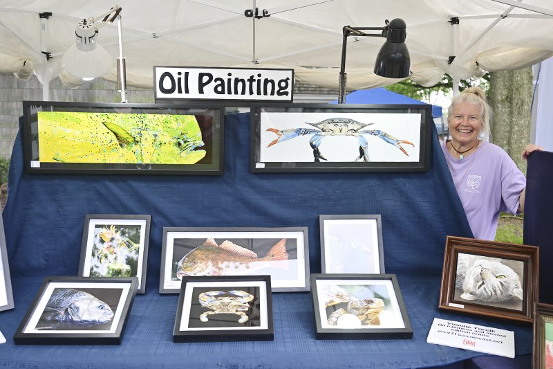 Artist Yvonne Torelli stands behind her paintings.