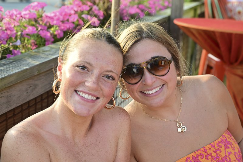 Emily Burns, left, and Hailey Ward take a break from signing in guests to pose for a photo.