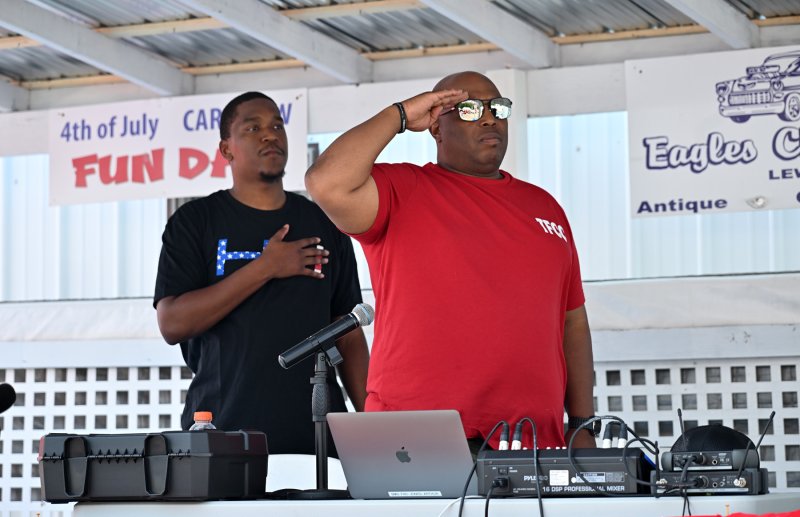 DJ 1Luv (Arthur Jones) salutes as Tevonne Bailey stands at attention during the national anthem.