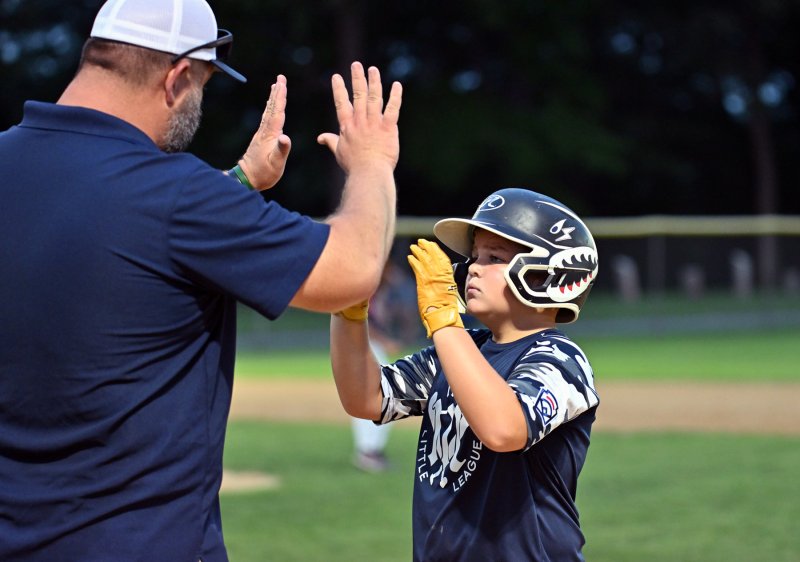 Milton’s Brock Davis gets congratulations on his hit from coach Jordan Reynolds.