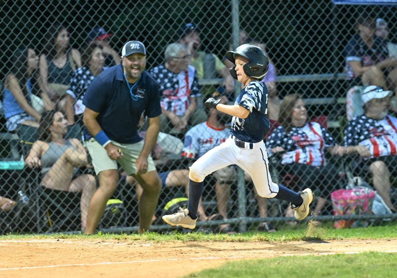 Milton manager Bob DeLacy watches as Henry Hill flies to home plate for a run.