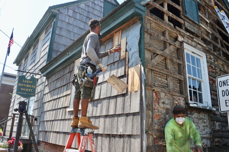 A worker removes some of the cedar shake at the start of the Cannonball House renovations July 29.