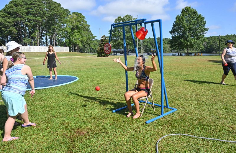 Athlete Ariana Froh and counselor Brianna Porter hit the target to soak Sara Perrotta at the splash tower.