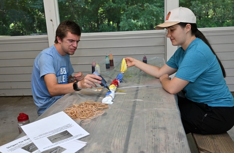 Athlete Austin Quackenbush works on his tye-dye shirt with Special Olympics Delaware Director of Development Erica Kelble.