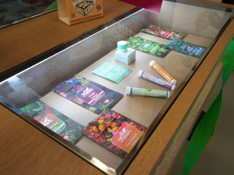 Several cannabis products in colorful packaging are on display in glass cases.