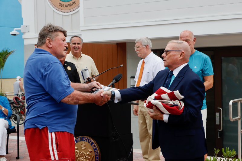 Pete Hartsock, left, a former Rehoboth Beach Patrol lieutenant, presents a star-spangled banner to State Archivist Stephen Marz at the dedication ceremony. The American flag has 15 stars and 15 stripes, like the one that flew over Fort McHenry. Marz said the flag will be maintained in the public archives.