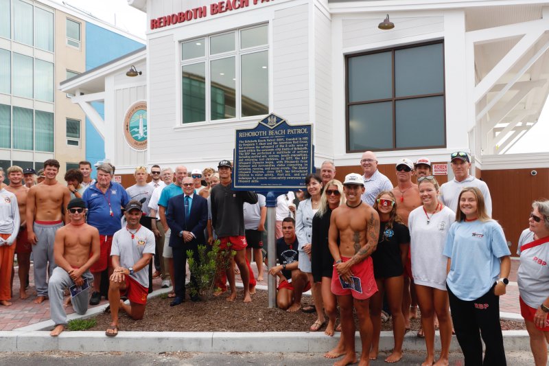 Current and former members of the Rehoboth Beach Patrol gathered in front of the new historical marker outside the beach patrol headquarters.