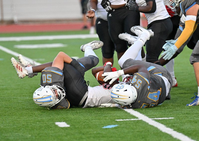 Linebacker Robbie Payton, left, and defensive lineman Christopher Harris take down Aydan Rutto.