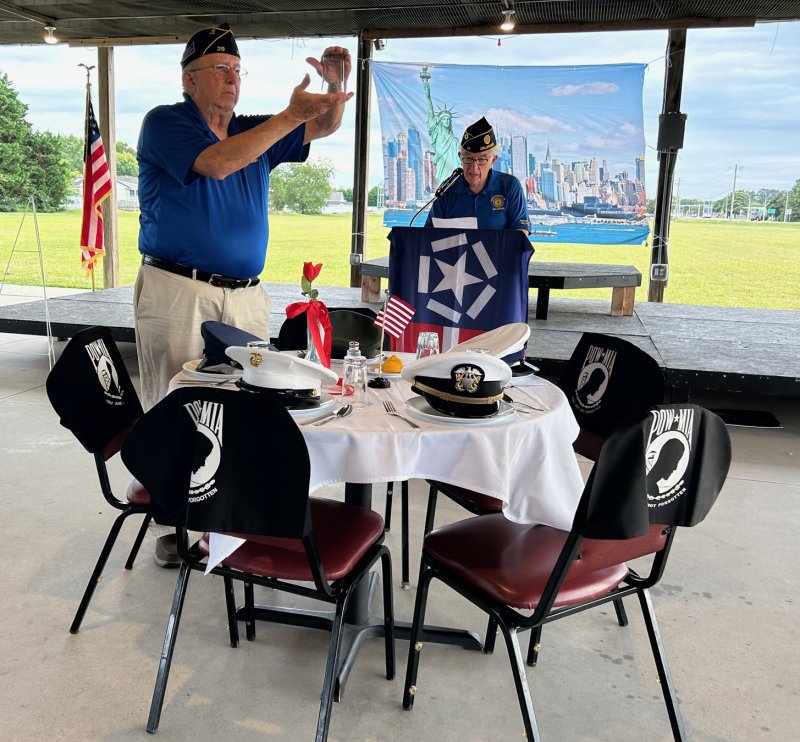Lee Glasco, left, and Jim Lafferty conduct a ceremony honoring POWs and those missing in action by setting a table, with each item on the table having symbolic meaning.