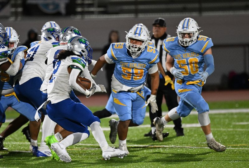 Sophomore Javier Morales-Roblero, 59, and senior Robbie Payton get a line on Hawks’ ball carrier Ayden Jones.