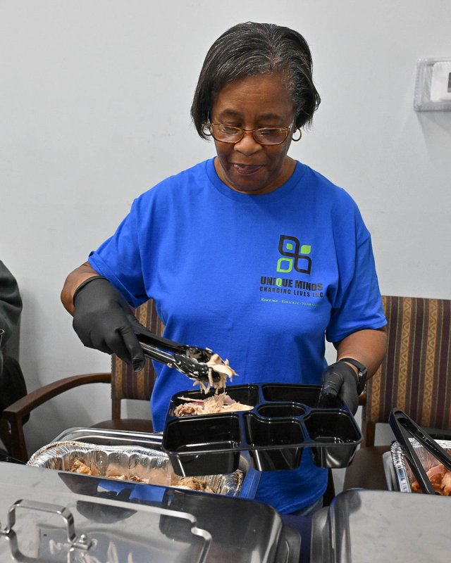 Debbie Trammell, member of Unique Minds Changing Lives’ board of directors, fills the food plates.