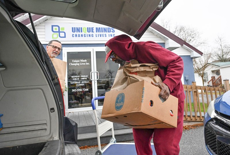 Unique Minds volunteer Victor Knowles loads a food box as Westminster Presbyterian Church volunteer Jim Miller awaits his turn.