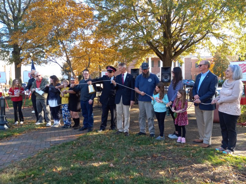 Attendees and officials help ring the bell as the official kickoff.
