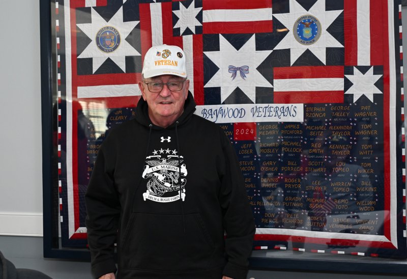 Marine veteran Bill Gaeckle stands in front of the Baywood Veterans Quilt of Valor presented by the Baywood Quilters at last years celebration. The quilt honors the service members of Baywood. DAN COOK PHOTOS