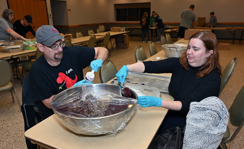 Daniel Cox, left, and Melanie Griego fill the cranberry sauce cups.