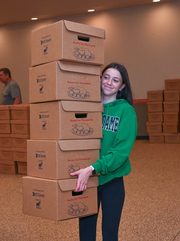 Makenna Cooper carries the boxes to be stocked with a turkey meal for first responders.