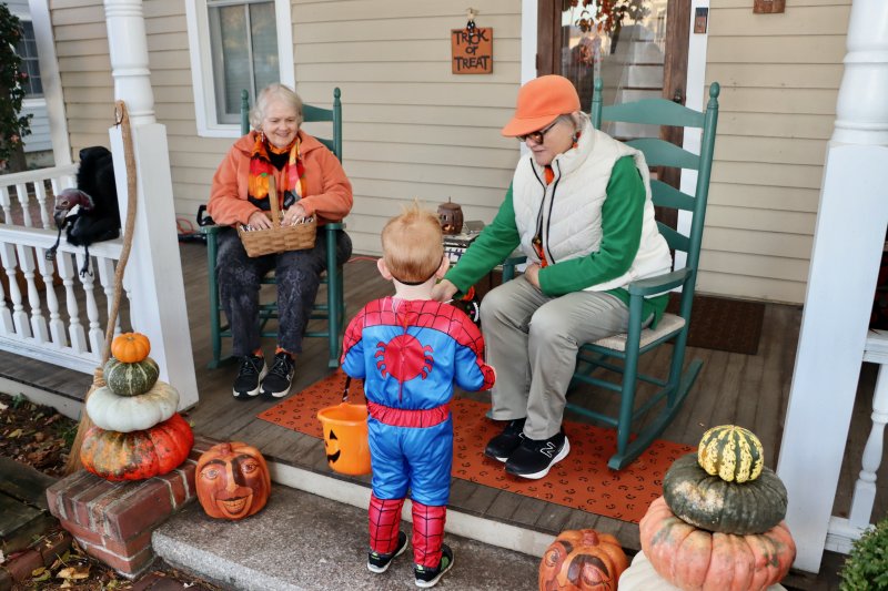 A young Spiderman takes some candy from Nancy Colalillo, left, and Janet Chapman at their home on Kings Highway.