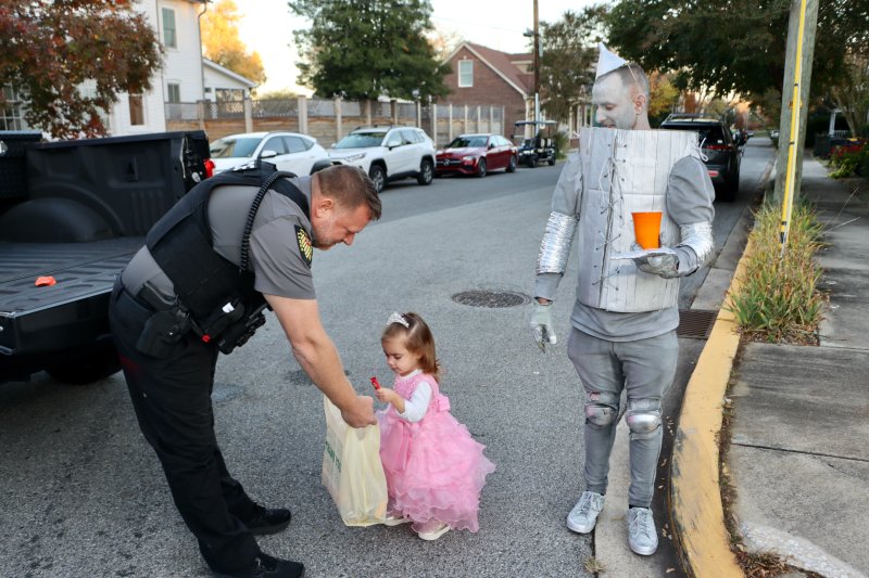 Lt. James Azato lets Bambi Wilkinson Corea grab some candy, while dad Sean Corea, as the tin man, looks on.