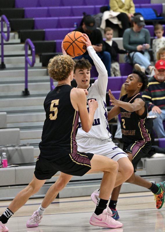 Royals sophomore Asher Woods splits the defense of the Jags’ Joshua Travers, left, and Forrez Davis.