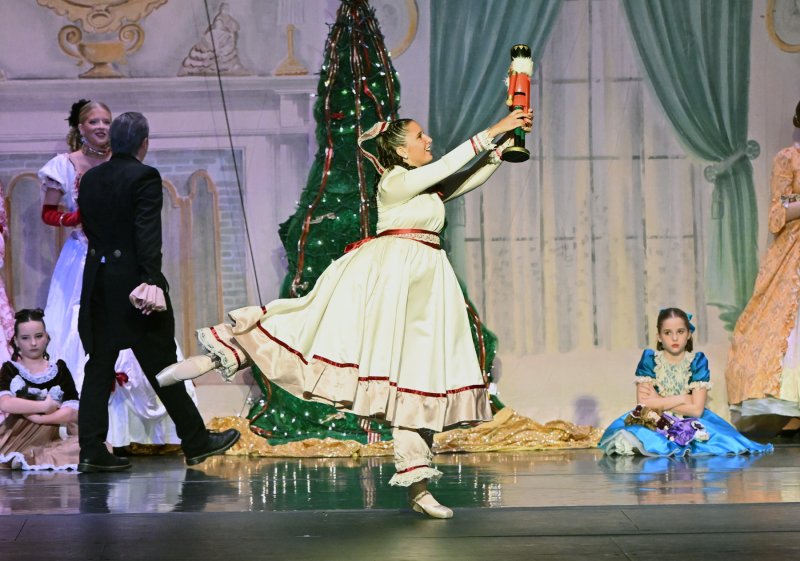 Clara receives the gift of the nutcracker doll as the envious party girls look on.