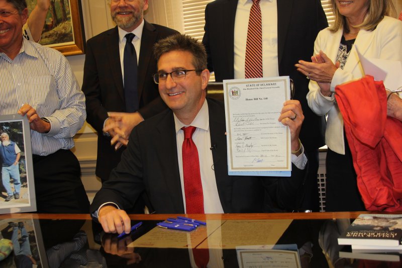 Gov. Matt Meyer holds up the new end-of-life options bill signed May 20. MELISSA STEELE PHOTO