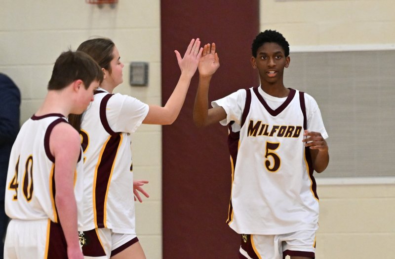 Milford’s Kenneth Deputy, right, gets a high five from a teammate for his basket.
