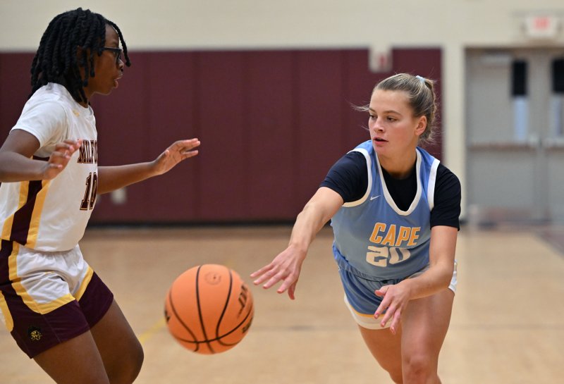 Cape junior Ally Diehl passes down low around Milford’s Mercedes Palmer.