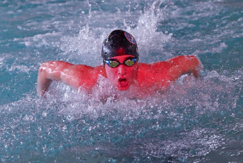 The reflection of the red scoreboard lights gives Weston Bohl a sunburned hue in the medley relay.