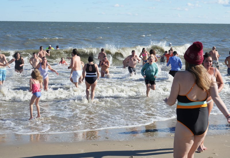 A wave crashes as Dewey Dunk participants brace for the cold.