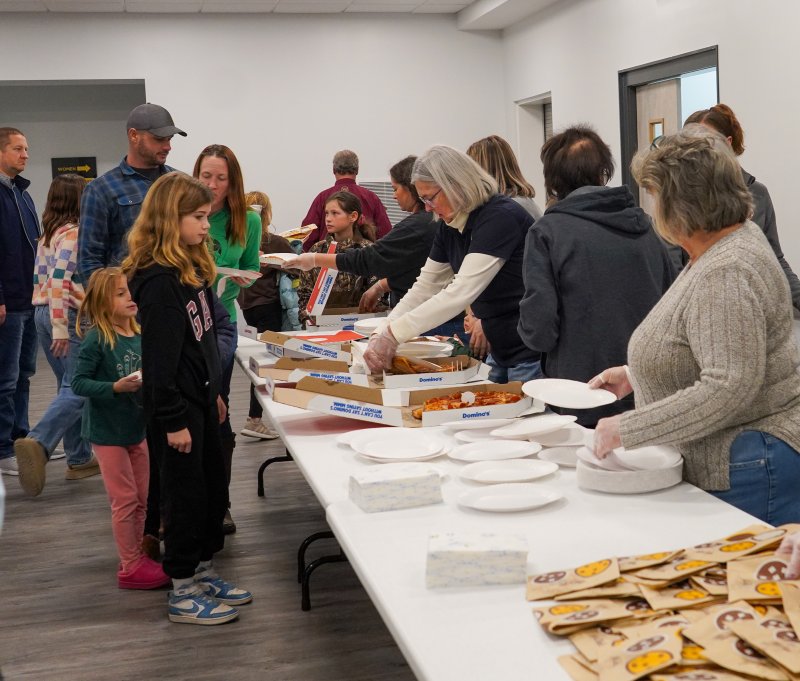 Members of the Milton Fire Department serve pizza to the assembled students.